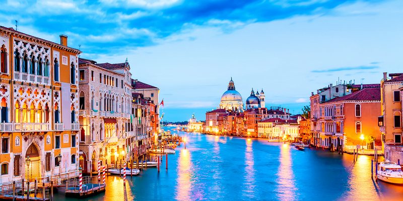 Basilica Santa Maria della Salute, Punta della Dogona and Grand Canal at blue hour sunset in Venice, Italy with boats and reflections